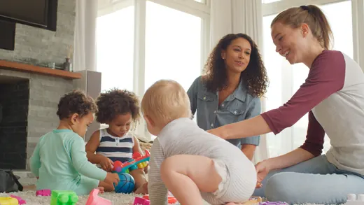 Bambini che giocano con le costruzioni sorvegliati dagli adulti